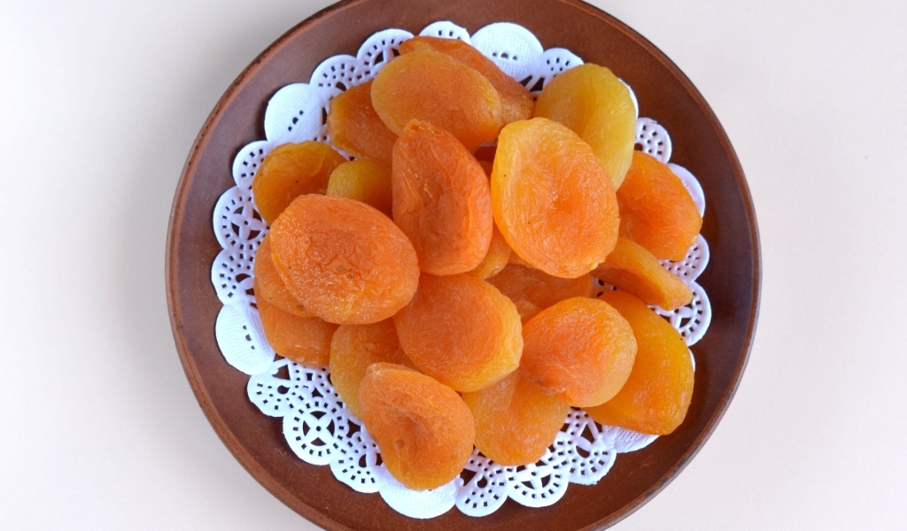 Курага с тарелке на сером фоне