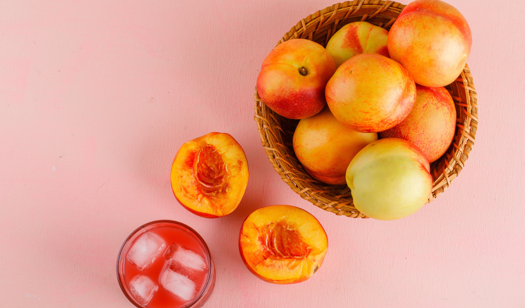 Свежий нектарин в корзине на розовом столе