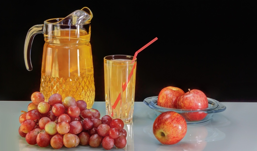 Виноград и яблоки на столе с соком