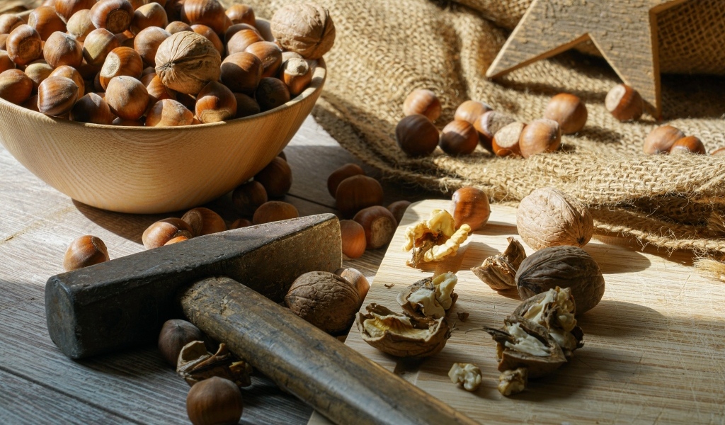 Фундук и грецкие орехи на столе с молотком