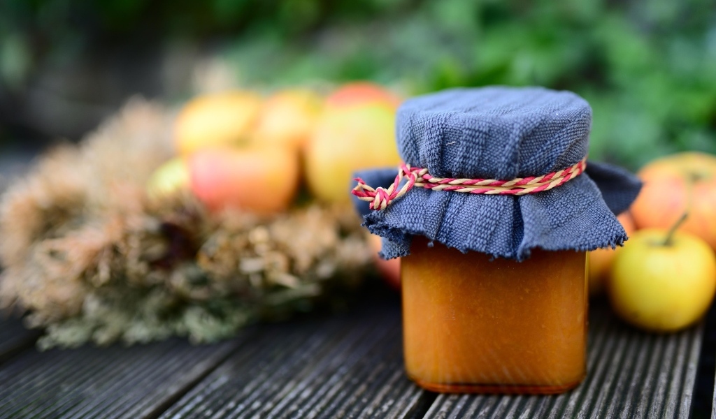 Банка яблочного джема на столе крупным планом