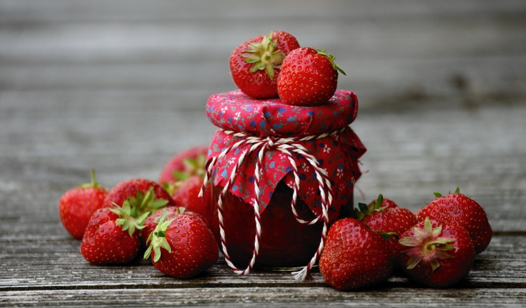 Банка джема на столе со свежими ароматными ягодами клубники