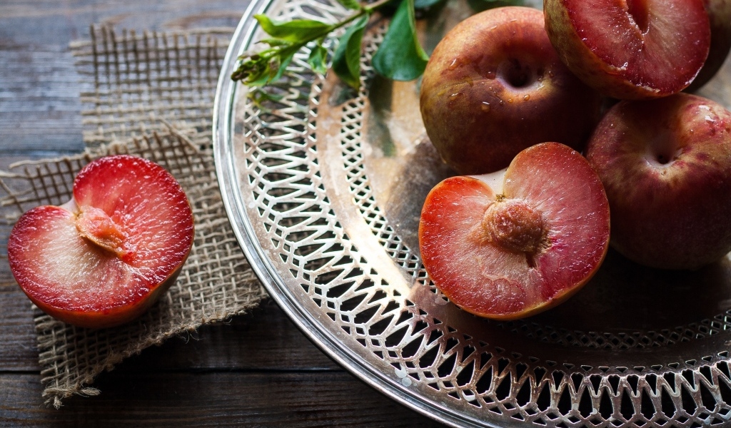 Сочные сливы на тарелке на столе