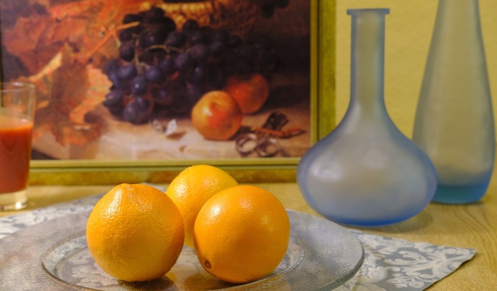 Три апельсина с вазами на столе