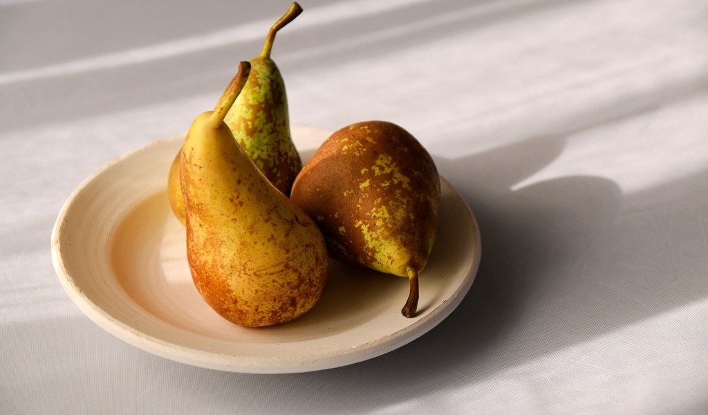 Три груши на тарелке на столе