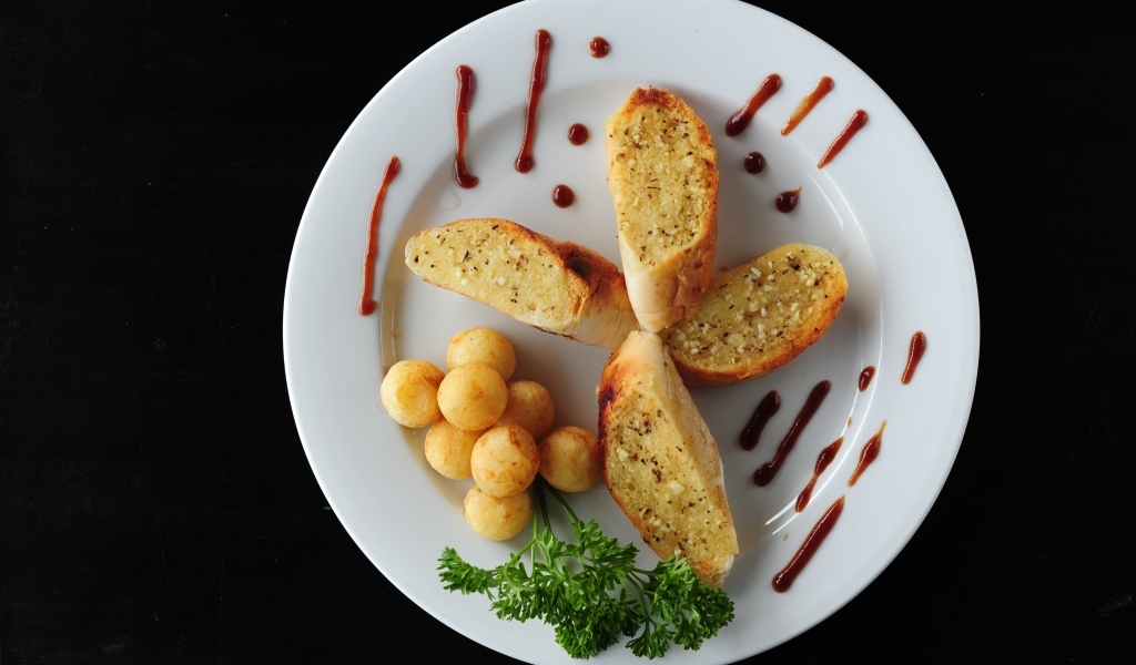 Чесночный хлеб на тарелке с картофельными шариками