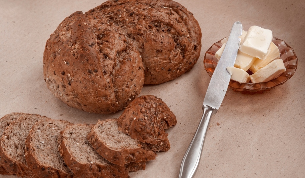 Ржаной хлеб со сливочным маслом и ножом на столе