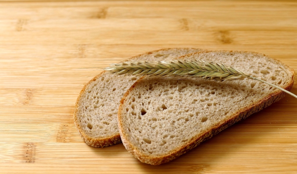 Два куска хлеба с колоском на деревянном столе