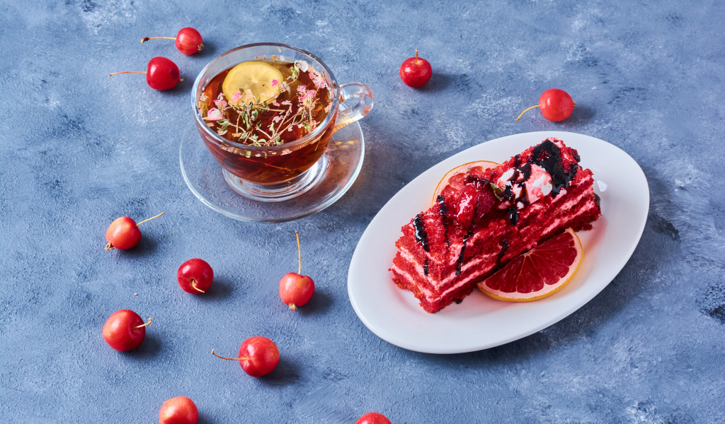 Аппетитный кусок торта на столе с чаем и ягодами черешни