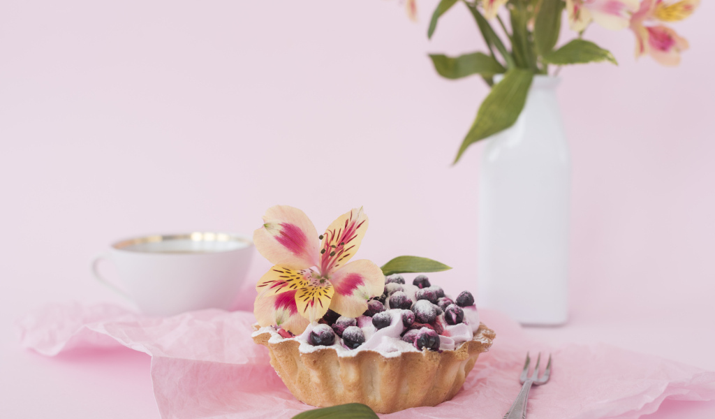 Черничное пирожное с цветами альстромерии на розовом фоне