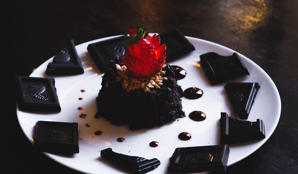 Десерт брауни на большой белой тарелке с шоколадом