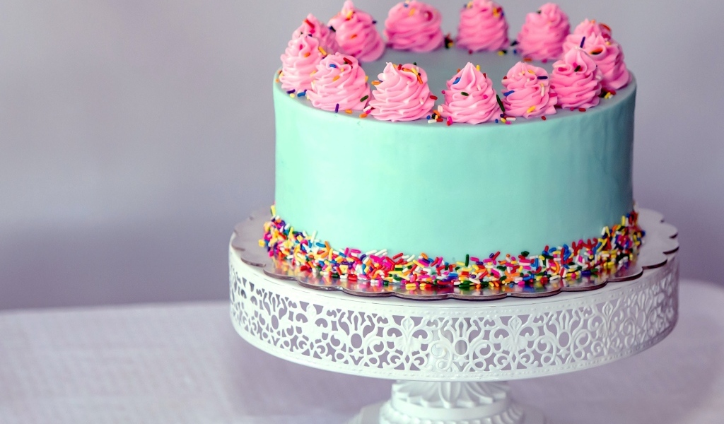 Торт с голубой глазури с розовым кремом на столе