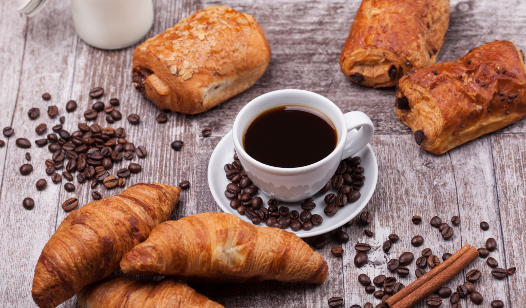 Кофе на столе с круассанами и зернами