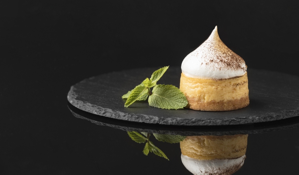 Десерт с кремом и листьями мяты на черном фоне