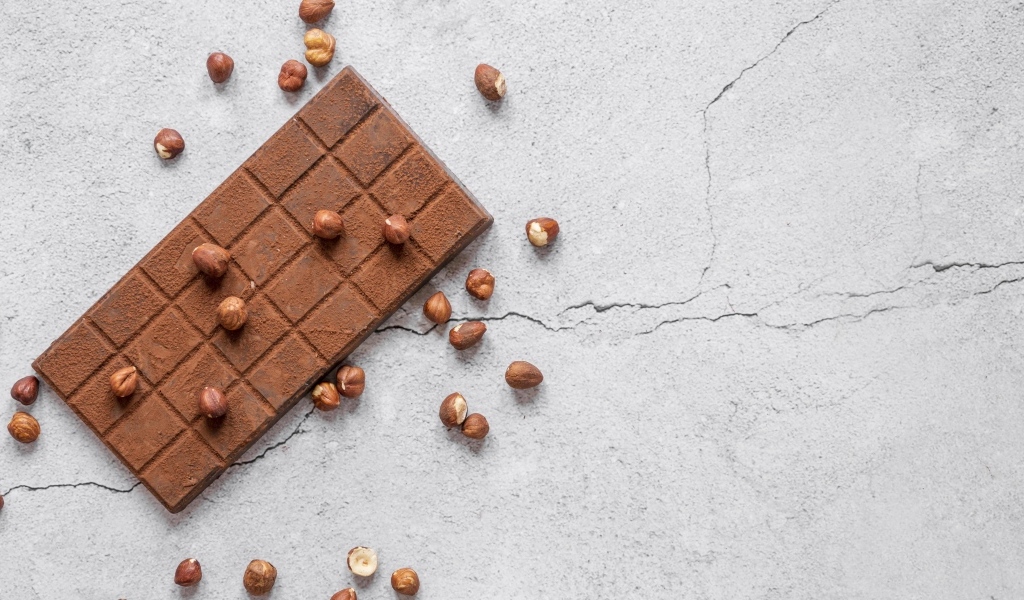Молочная шоколадка с орехами на сером столе