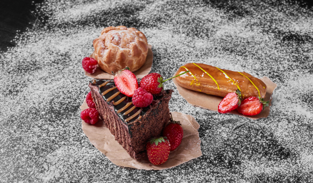 Кусок торта с ягодами на столе с эклером