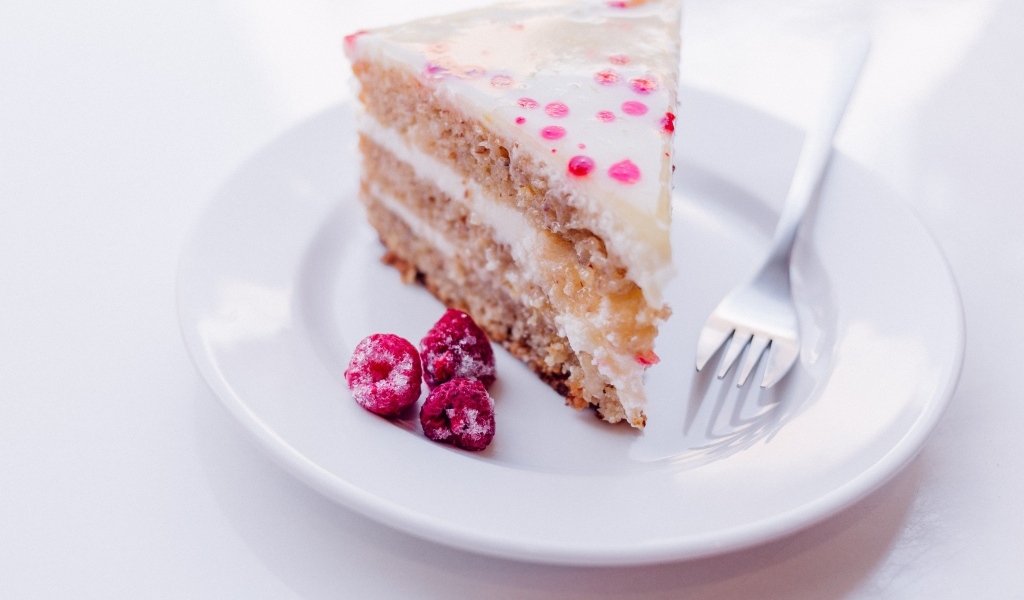Кусок торта с замороженной малиной на белой тарелке