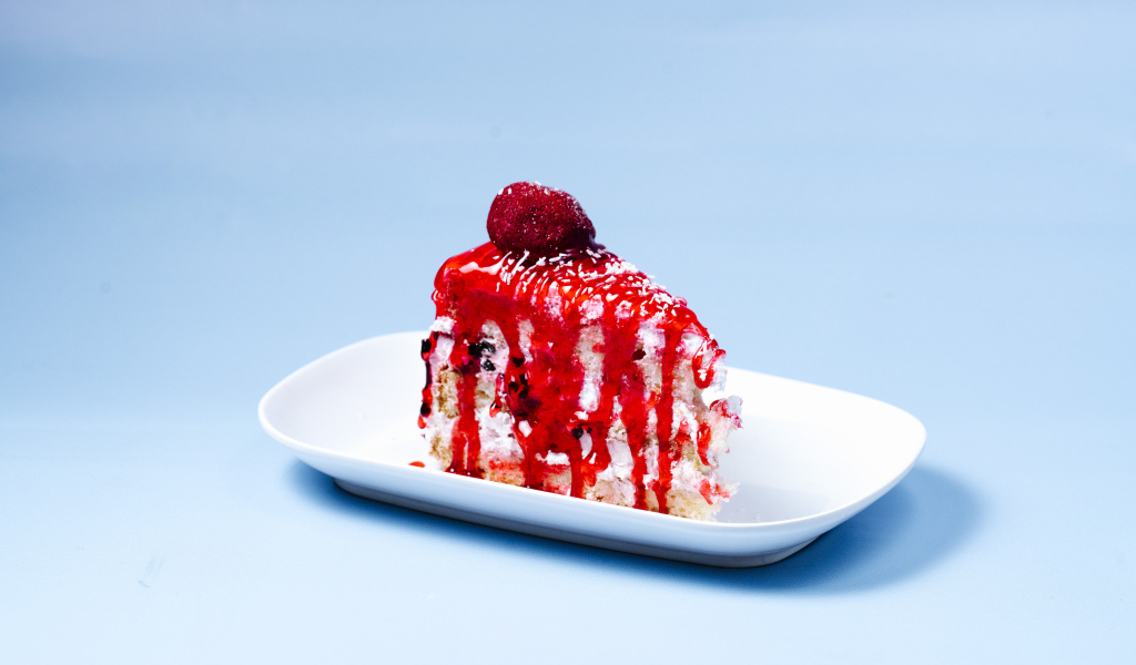 Кусок торта с клубничным сиропом на голубом фоне