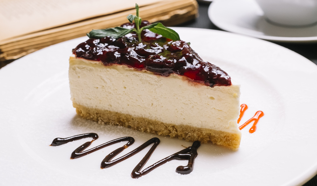 Кусок чизкейка с джемом на белой тарелке