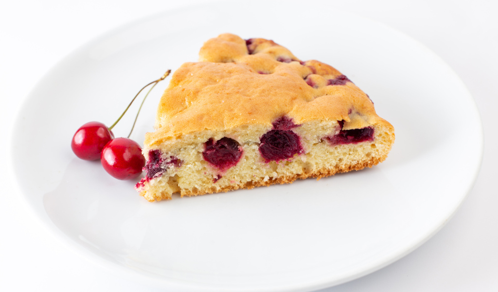 Кусок вишневого пирога с ягодами на тарелке