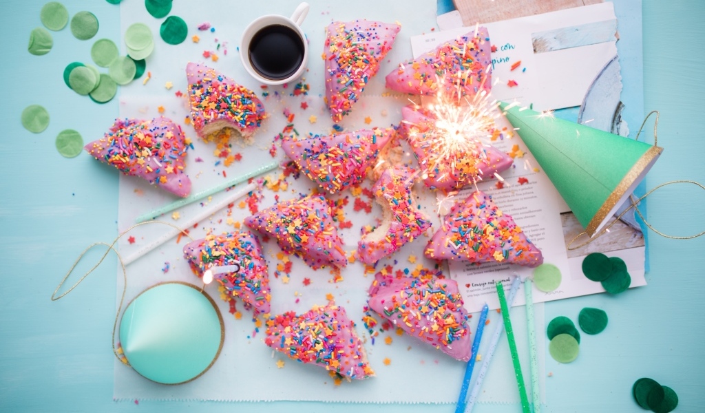 Кусочки торта в розовой глазури на столе с праздничным декором