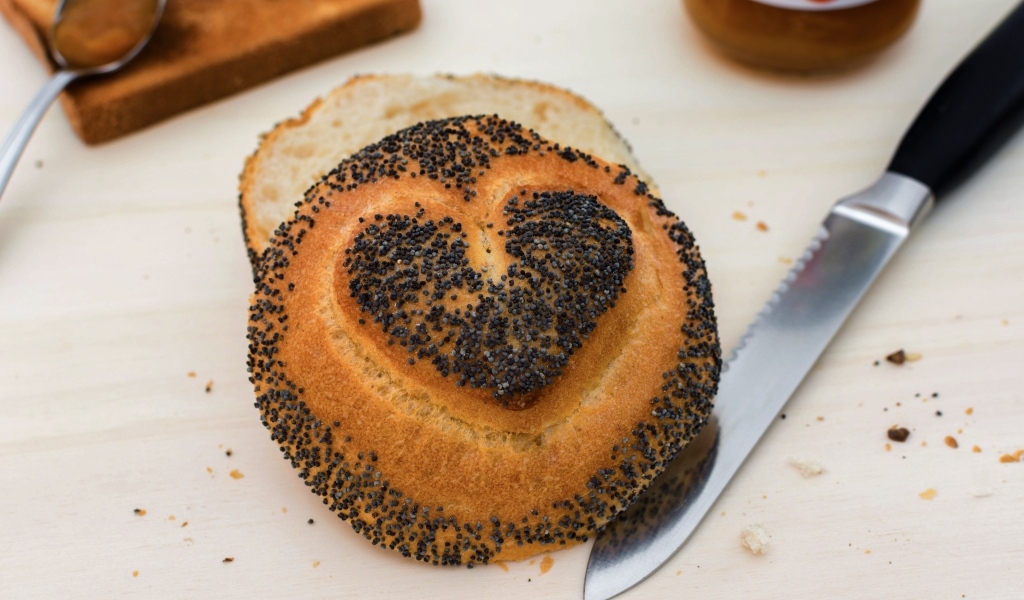 Булочка с маком с нарисованным сердцем на столе