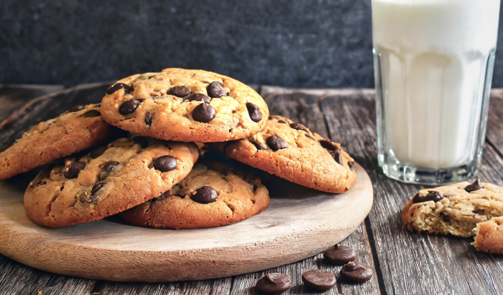 Круглое печенье с шоколадом на столе со стаканом молока