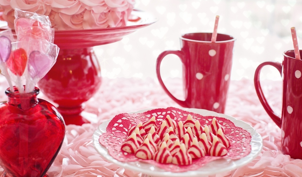Сладкие розовые конфеты на столе с чаем и тортом