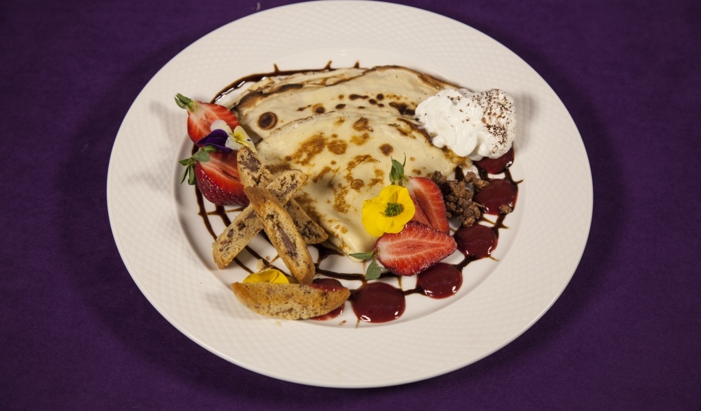 Тонкие блинчики с кремом и ягодами на тарелке