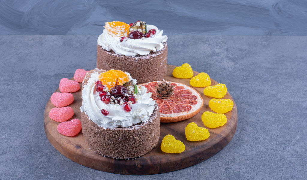 Два пирожных на деревянной доске с мармеладными конфетами