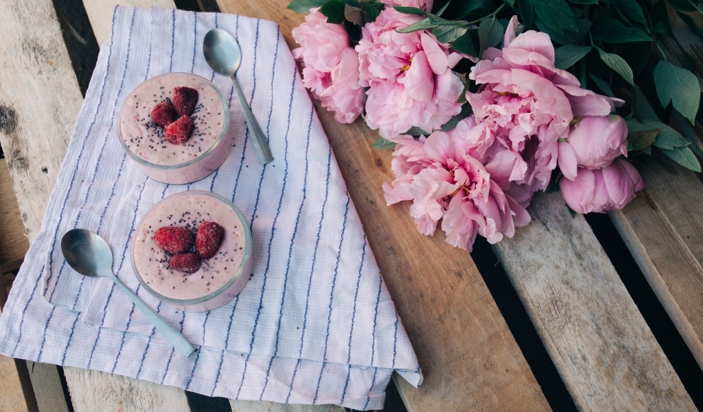 Два стакана с десертом на лавке с букетом пионов