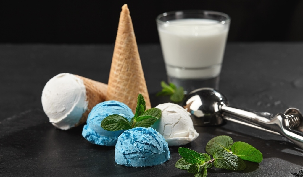 Вафельный рожок с шариками мороженого, мятой и молоком на столе