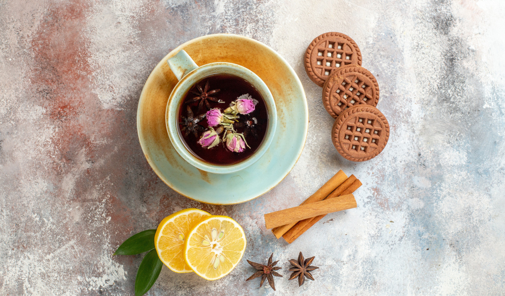 Чашка ароматного чая на столе с лимоном, печеньем и пряностями