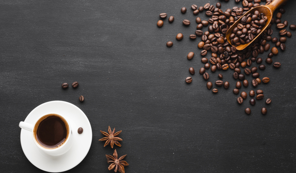 Чашка кофе на черном столе с зернами