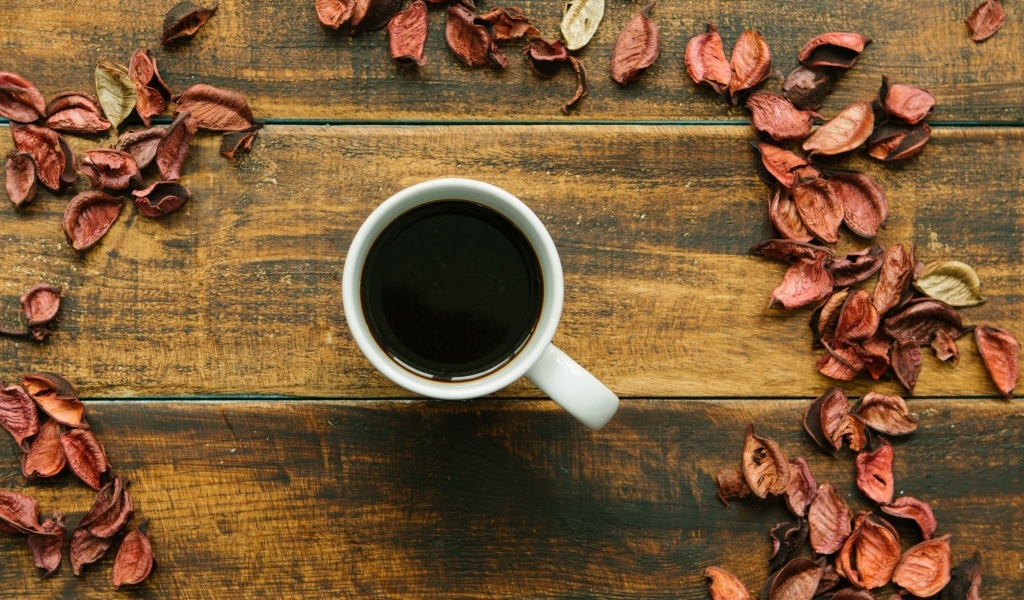 Чашка кофе с опавшими листьями на деревянном столе