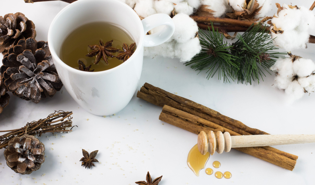 Чашка чая со специями на столе с хлопком и шишками