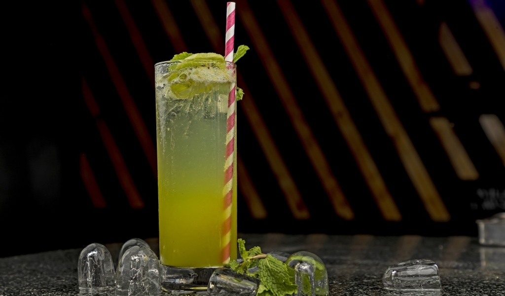 Зеленый коктейль мохито в высоком стакане со льдом