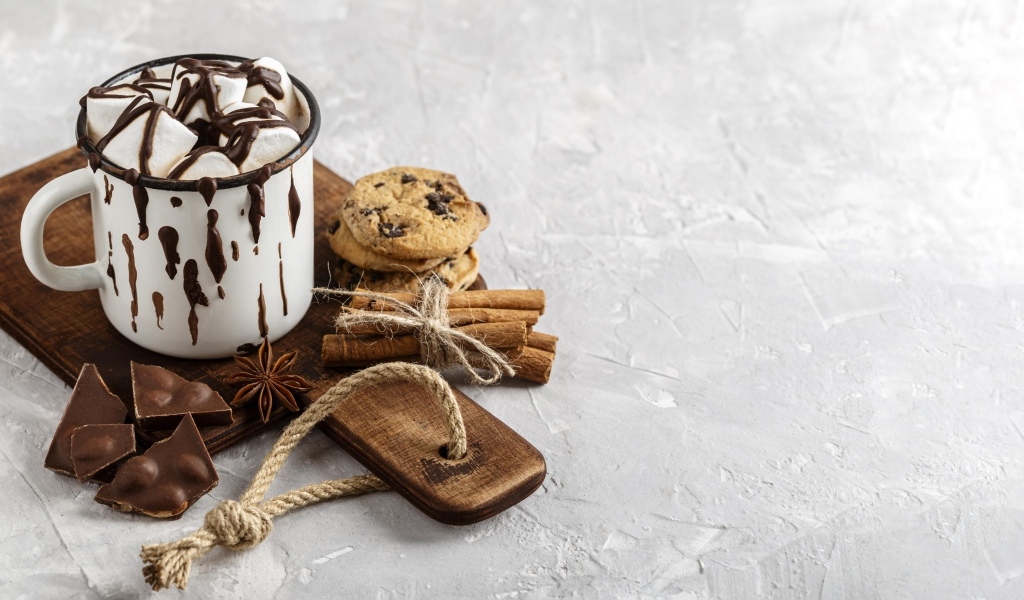 Горячий шоколад с маршмеллоу на столе с печеньем и конфетами