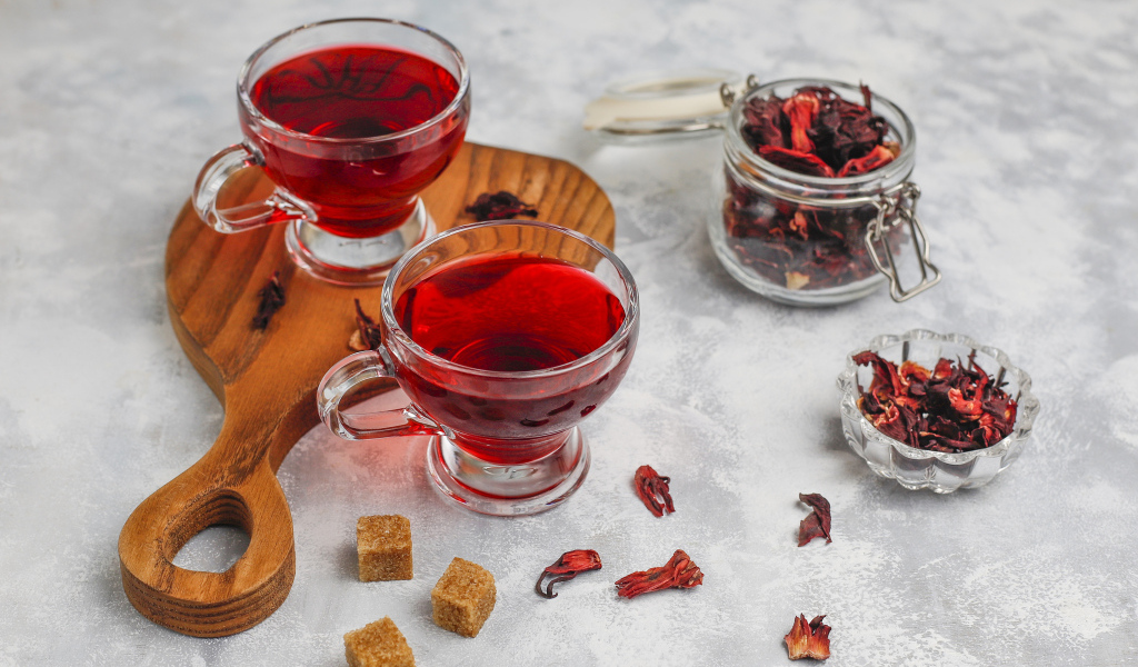 Две чашки чая каркаде на столе с заваркой 