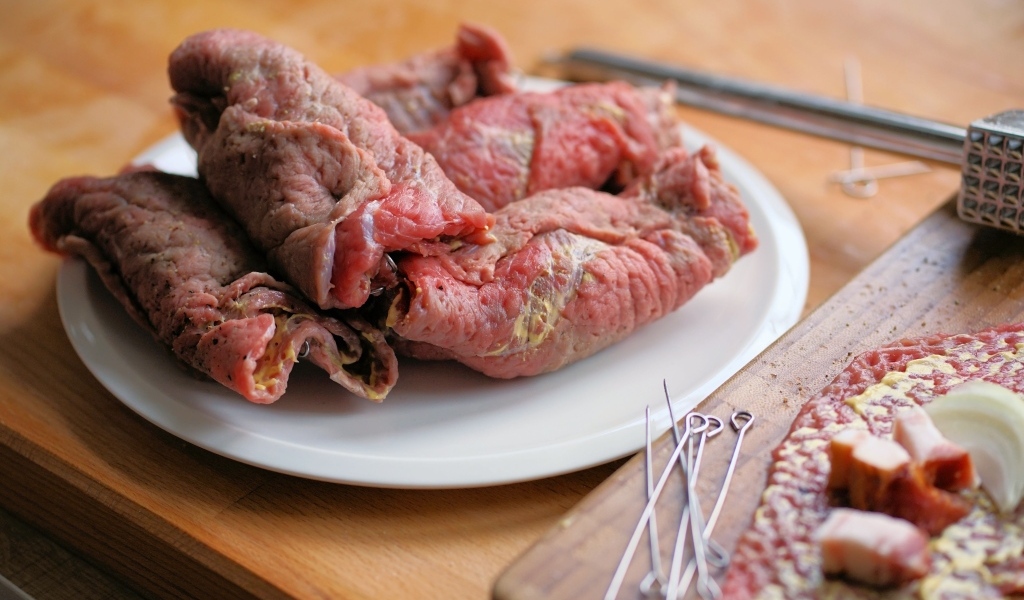 Рулетики из свинины на большой белой тарелке