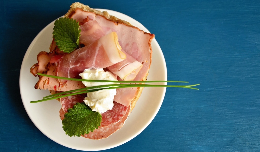 Бутерброд с колбасой и беконом на синем столе