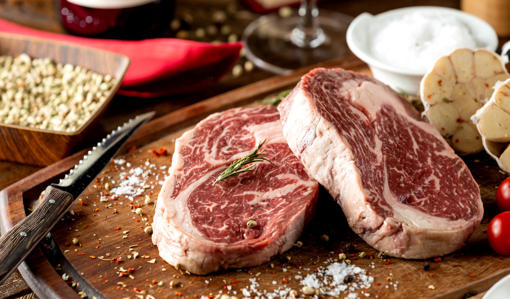 Два куска аппетитного стейка на столе со специями