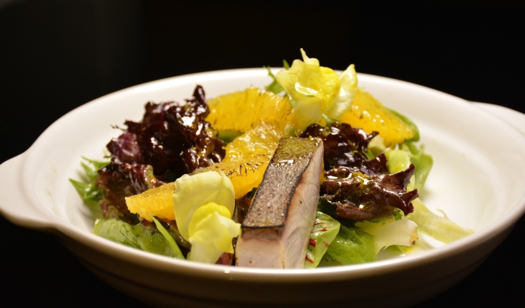 Кусочки рыбы с салатом и лимоном в тарелке