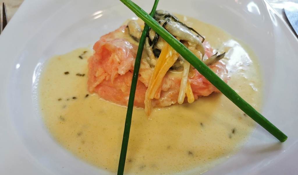 Красная рыба с соусом на тарелке с зеленым луком