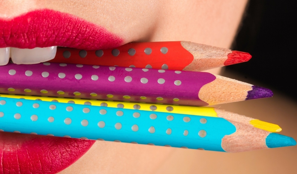Разноцветные карандаши в губах у девушки