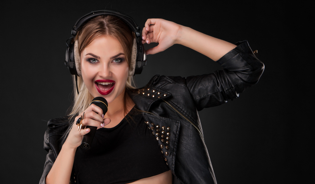 Девушка в черной кожаной куртке поет в микрофон