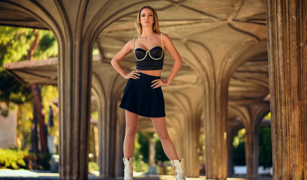 Девушка в короткой черной юбке стоит у здания