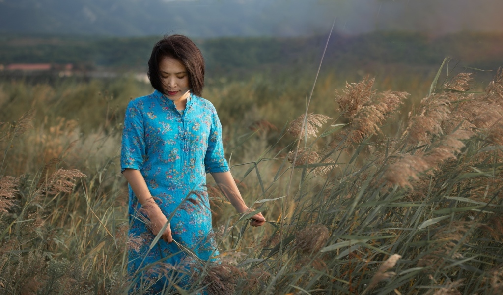 Девушка азиатка в платье на поле с колосьями