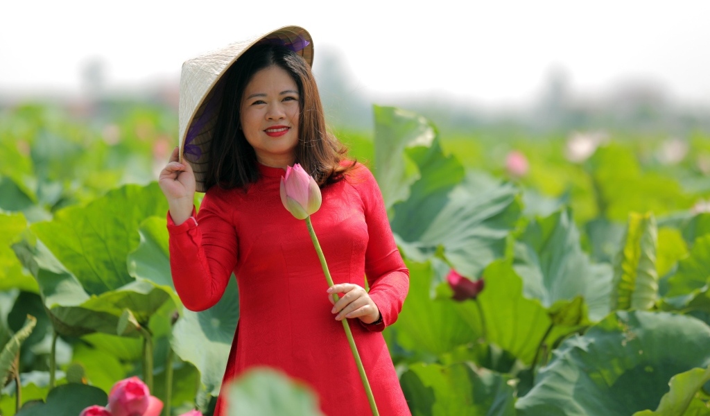 Девушка азиатка в красном платье у цветов лотоса