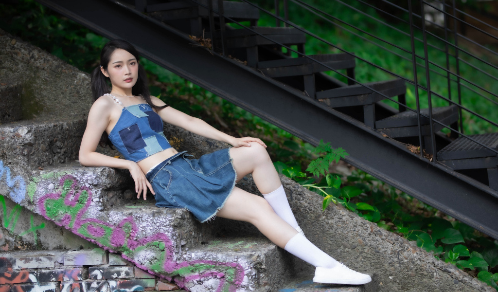 Девушка азиатка в юбке лежит на лестнице